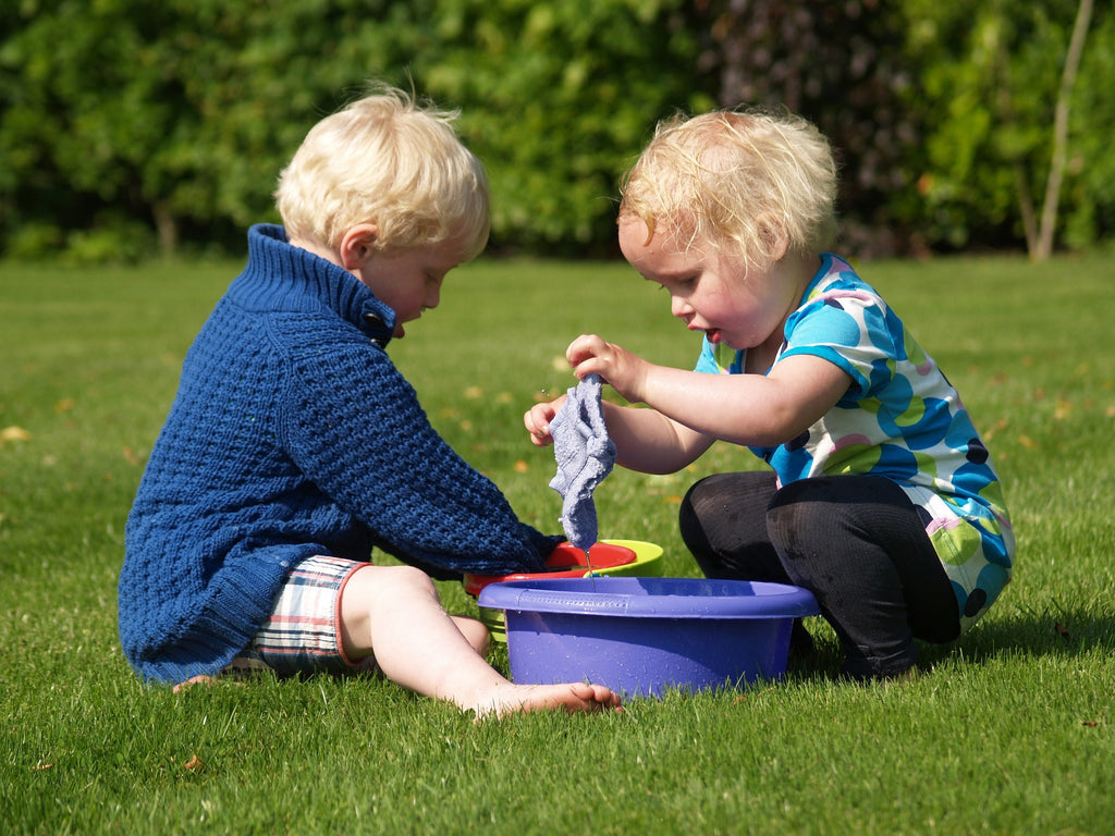 Two infants outside with water play.